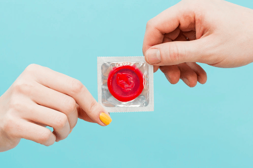 Imagem de uma mão feminina e outra masculina segurando um preservativo para simbolizar o que é donovanose