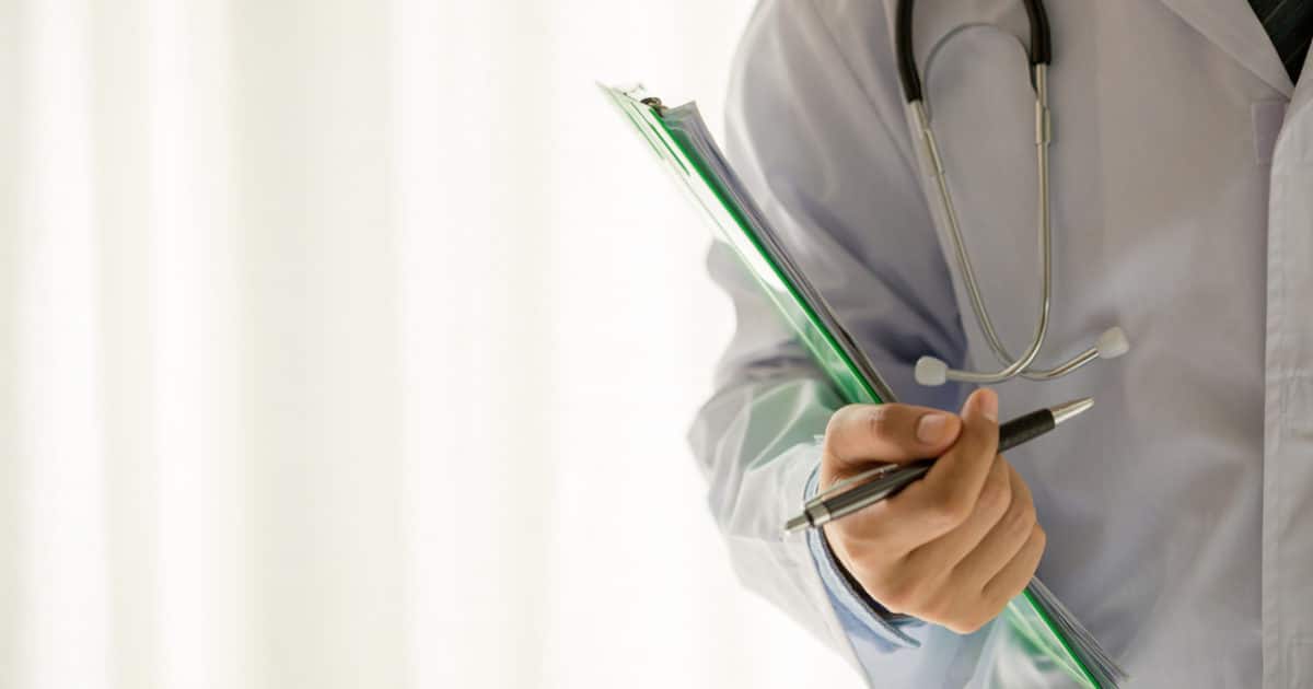 Imagem de um corpo de médico, com exames e caneta na mão para simbolizar ureteroscopia