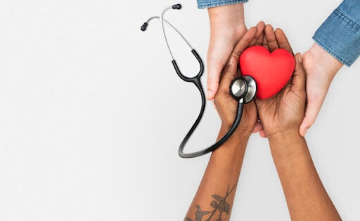 mãos tocando um coração e um equipamento médico para simbolizar o dia mundial da saúde